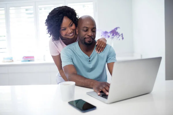 Kvinna som omfamnar man medan du använder laptop — Stockfoto