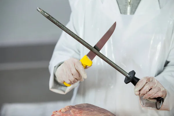 Female butcher sharpening his knife — Stock Photo, Image