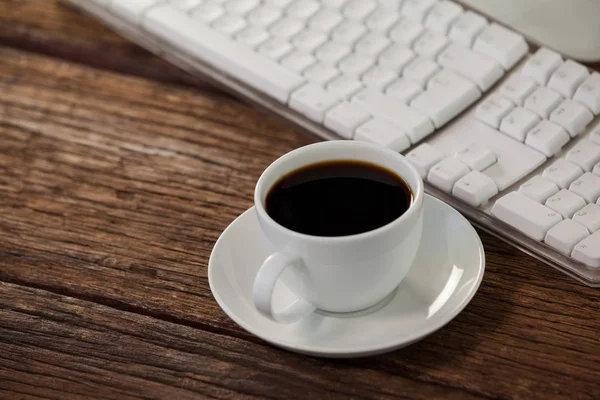 Šálek kávy vedle klávesnice — Stock fotografie