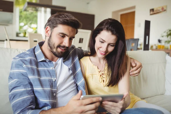 Casal usando tablet digital enquanto relaxa no sofá — Fotografia de Stock