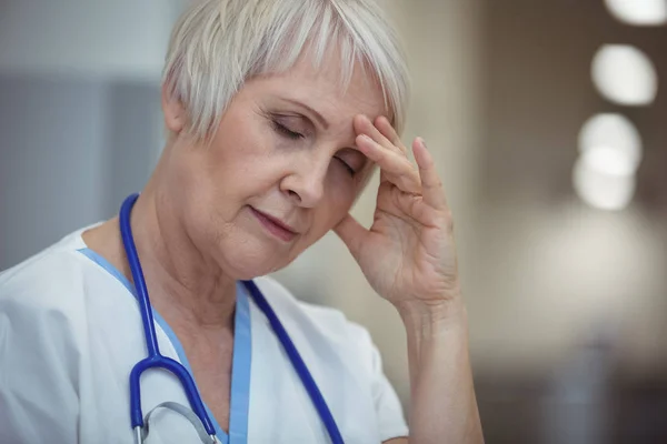 Tensed female nurse sitting in corridor — Stock Photo, Image