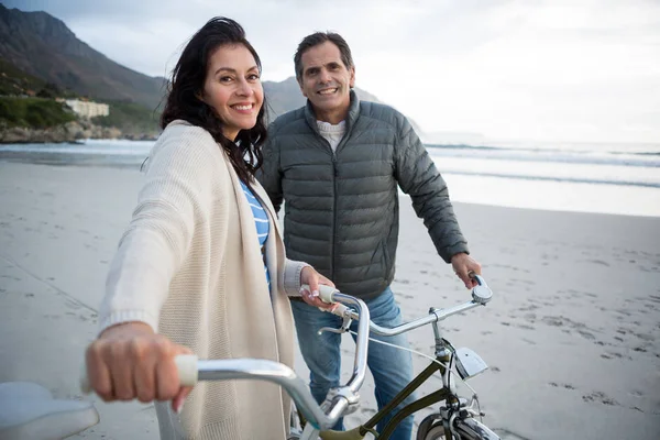 Coppia in piedi con bicicletta sulla spiaggia — Foto Stock