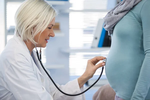 Médico examinando a una mujer embarazada con estetoscopio — Foto de Stock