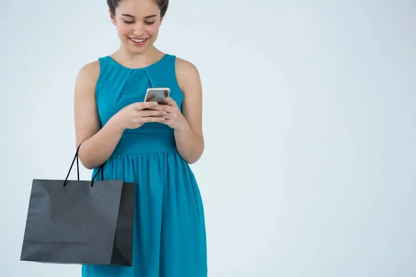 Mujer llevando bolsa de la compra y usando el teléfono — Foto de Stock