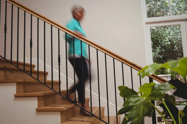 Senior woman walking down stairs — Stock Photo, Image