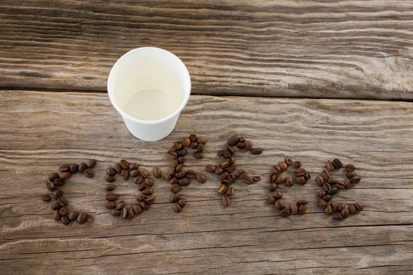 Grains de café disposés en mot de café avec des tasses jetables — Photo