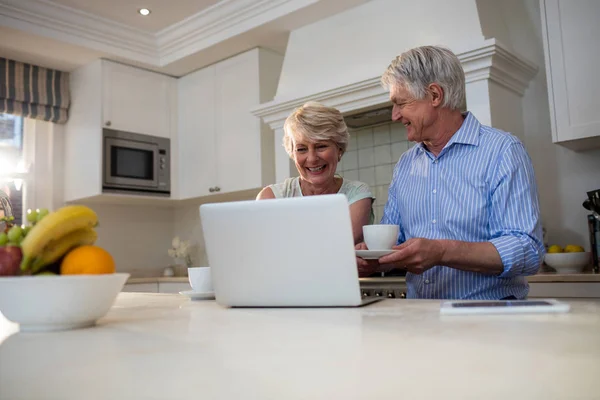 Senior couple using laptop having tea