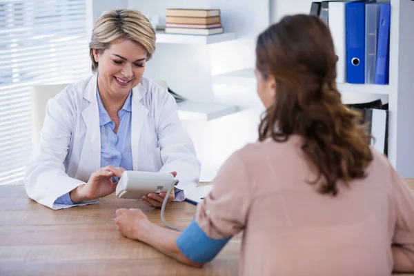 Medico donna che controlla la pressione sanguigna di un paziente — Foto Stock