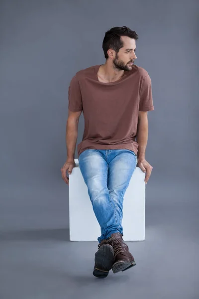 Man in brown t-shirt sitting on a block — Stok Foto