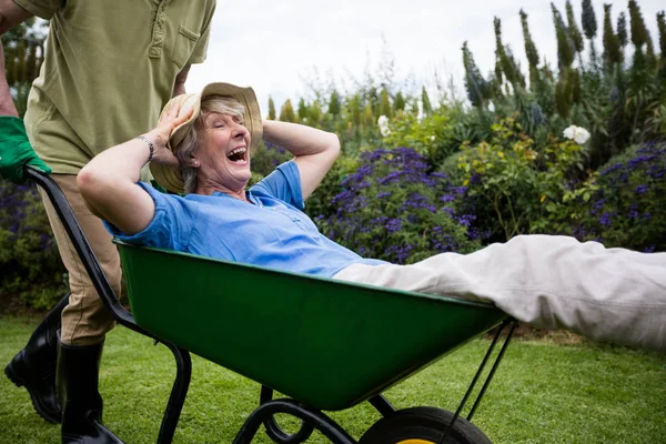 Senior mannen bära hans partner i skottkärra — Stockfoto