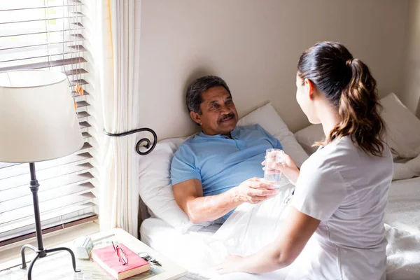 Läkare att ge vatten till äldre patient — Stockfoto