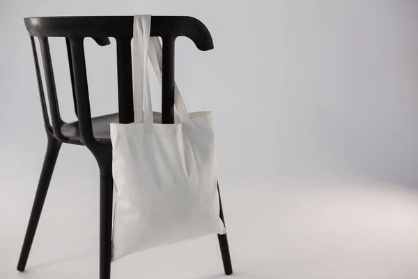 Sac blanc suspendu sur une chaise noire — Photo