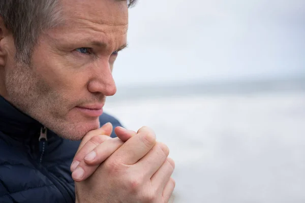 Nachdenklicher Mann mit gefalteten Händen am Strand — Stockfoto