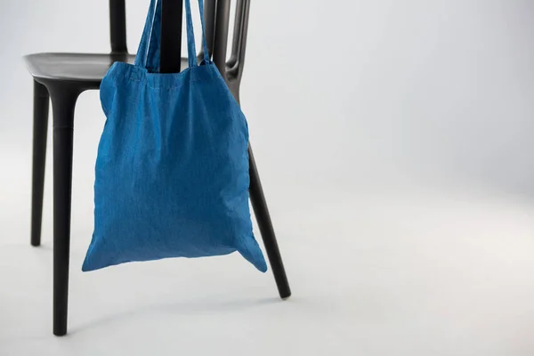 Блакитна сумка, що висить на чорному стільці — стокове фото