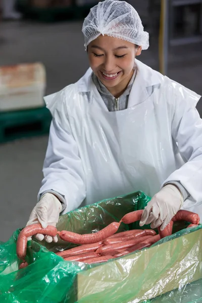 Female butcher processing sausages — Stock Photo, Image