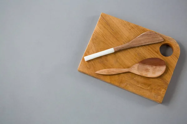 Wooden knife and spoon on chopping board — Stock Photo, Image