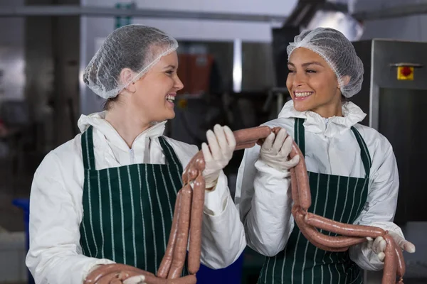 Carniceiros fêmeas processando salsichas — Fotografia de Stock