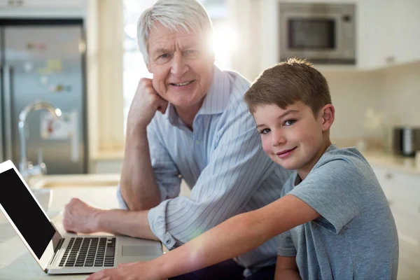 Nieto y abuelo con portátil en la cocina — Foto de Stock