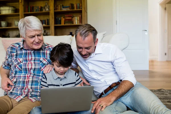 Boy using laptop with his father and grandfather — Stock Photo, Image