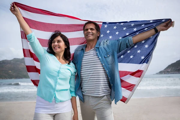 Coppia che tiene bandiera americana sulla spiaggia — Foto Stock