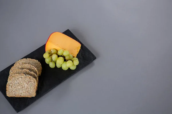 Queijo Gouda, uvas e fatias de pão castanho — Fotografia de Stock