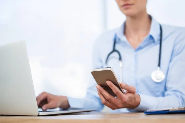 Lekarz za pomocą laptopa i telefonu komórkowego — Zdjęcie stockowe