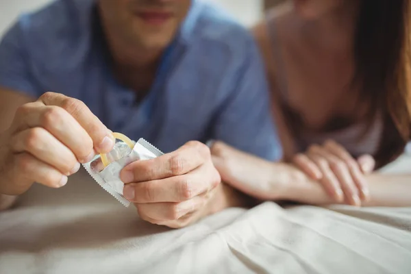 Casal com um preservativo na cama — Fotografia de Stock