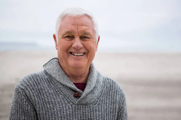 Sonriente hombre mayor de pie en la playa — Foto de Stock