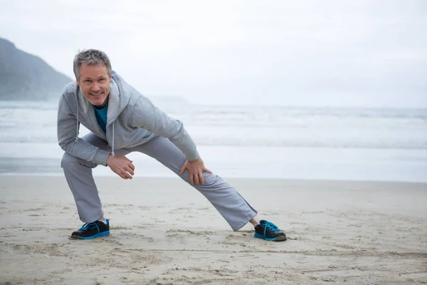 Homme effectuant des exercices d'étirement sur la plage — Photo