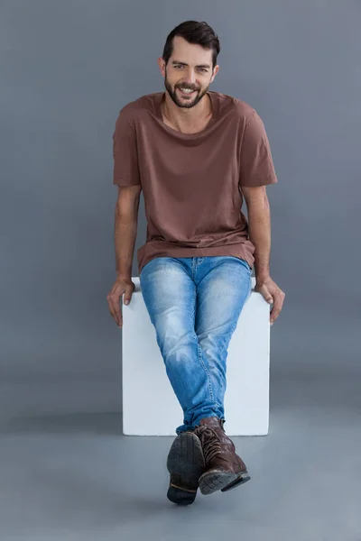 Hombre de camiseta marrón sentado en un bloque —  Fotos de Stock