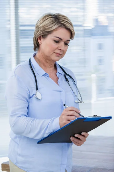 Female doctor writing on clipboard — Stock Photo, Image