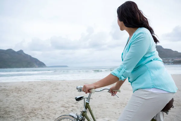 Mulher de pé com bicicleta na praia — Fotografia de Stock