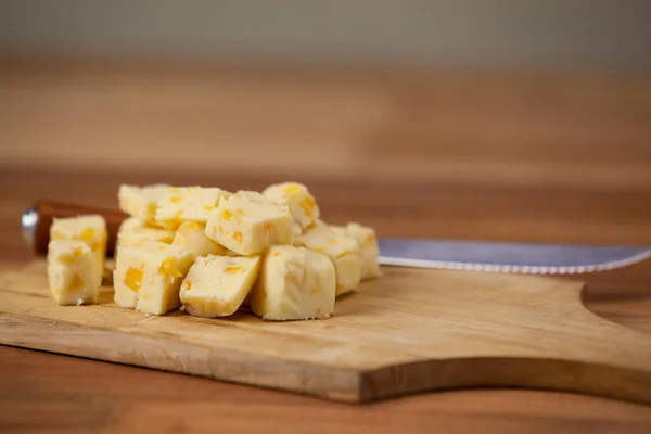 Cubos de queso sobre tabla de cortar de madera — Foto de Stock