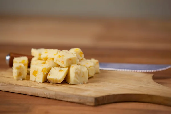 Cheese cubes on wooden chopping board — Stock Photo, Image