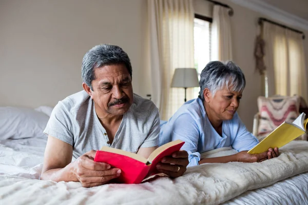 Äldre par läsa böcker på sängen — Stockfoto