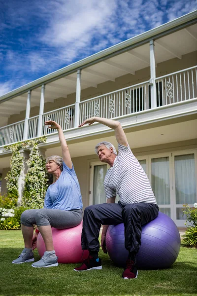 Pareja realizando ejercicio de estiramiento en la pelota de fitness — Foto de Stock