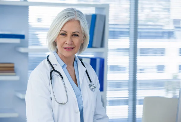 Sorridente feminino médico sentado na mesa — Fotografia de Stock