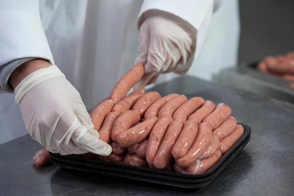 Butcher packing raw sausages — Stock Photo, Image