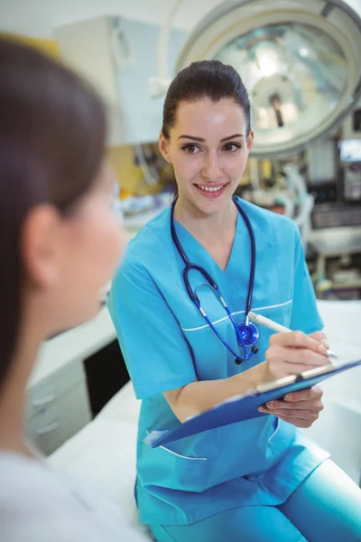 Female nurse writing on clipboard — Stock Photo, Image