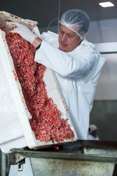 Мясник опорожняет поднос мясом. — стоковое фото