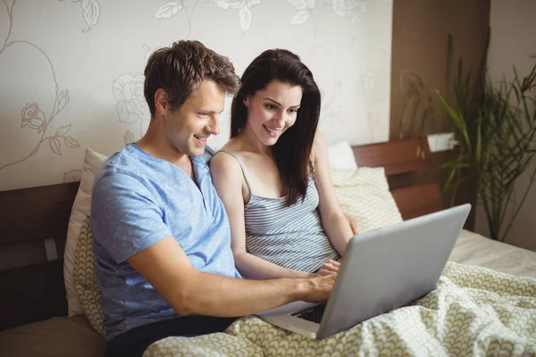 Casal feliz usando laptop na cama — Fotografia de Stock