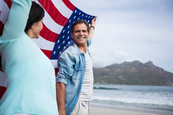 Casal segurando bandeira americana na praia — Fotografia de Stock