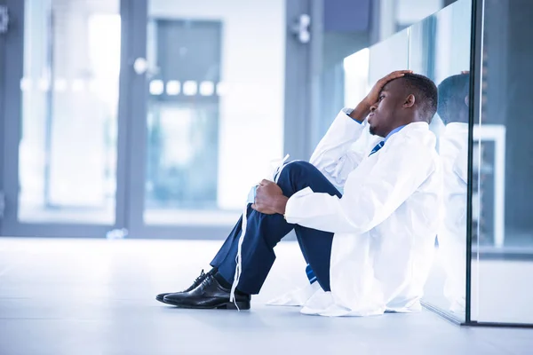 Médico preocupado sentado no chão — Fotografia de Stock