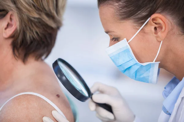 Dermatologist examining mole of female patient — Stock Photo, Image