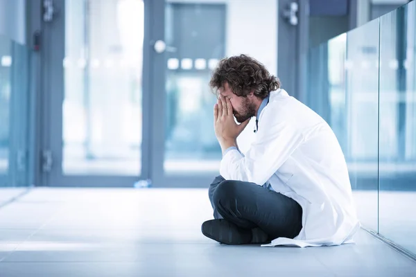 Besorgter Arzt sitzt auf dem Boden — Stockfoto