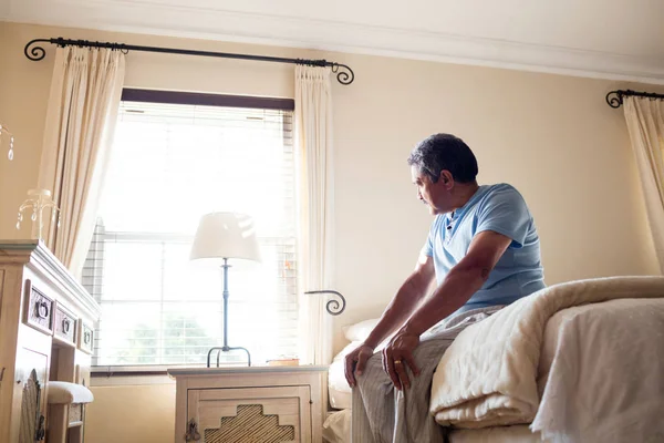 Nachdenklicher Senior blickt durch Fenster — Stockfoto