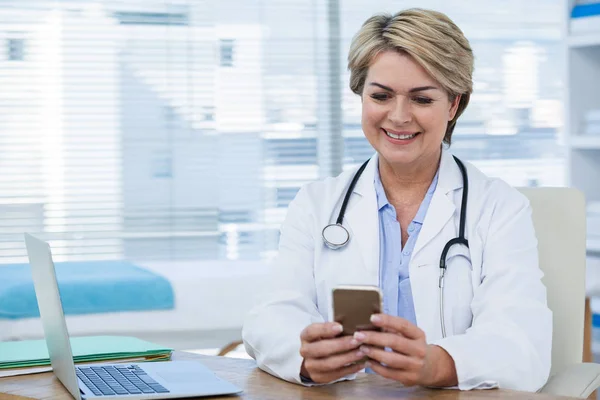 Ärztin benutzt Telefon mit Laptop — Stockfoto