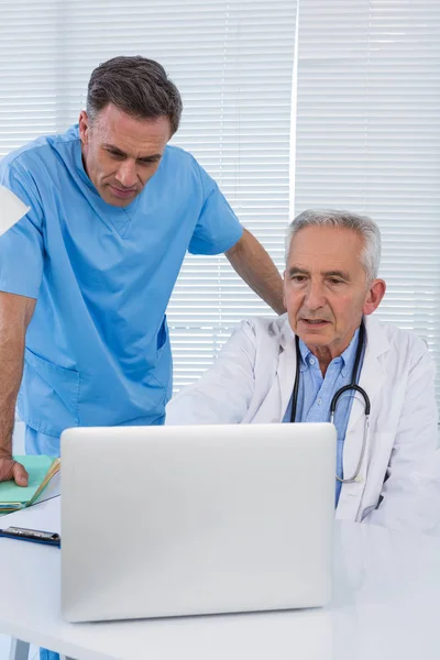 Χειρούργος και γιατρός συζητώντας πάνω από φορητό υπολογιστή — Φωτογραφία Αρχείου