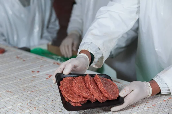 Açougueiro detentor de rissóis de carne crua dispostos em bandeja — Fotografia de Stock
