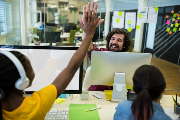 Ejecutivos de negocios dando cinco altos en el escritorio — Foto de Stock